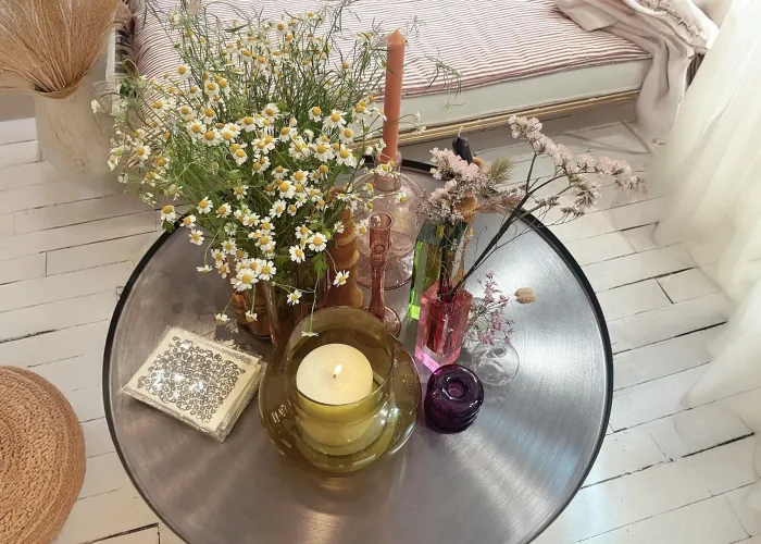 Bougie allumée et bouquet de marguerites sur un plateau rond en métal