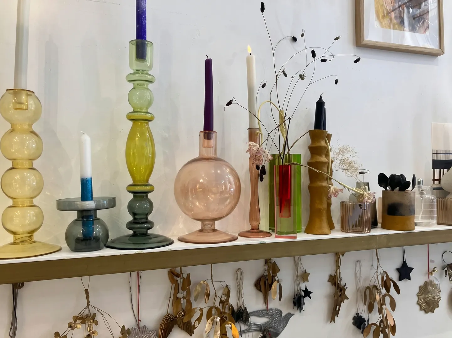Photophores et bougeoirs en verre coloré sur une étagère