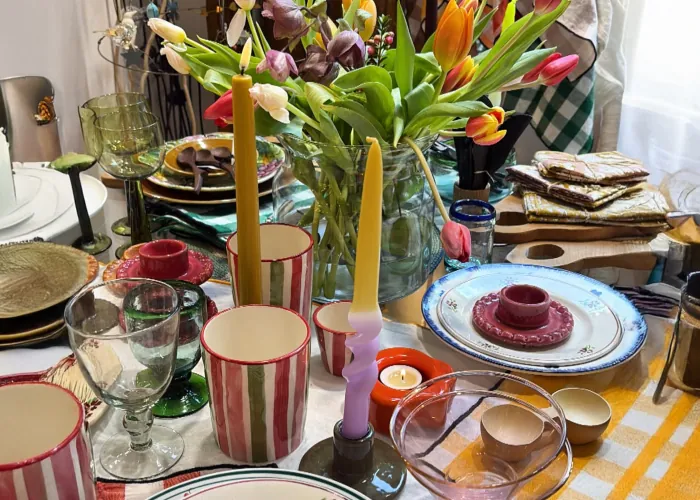 Table garnie de tulipes, de bougies colorées, de verres et d'assiettes peintes