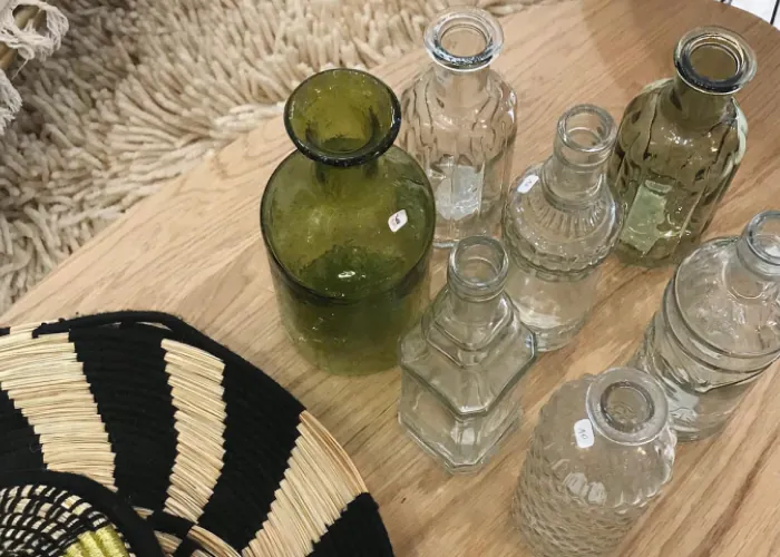 Carafes et petits vases en verre, vert et transparent, sur une table en bois