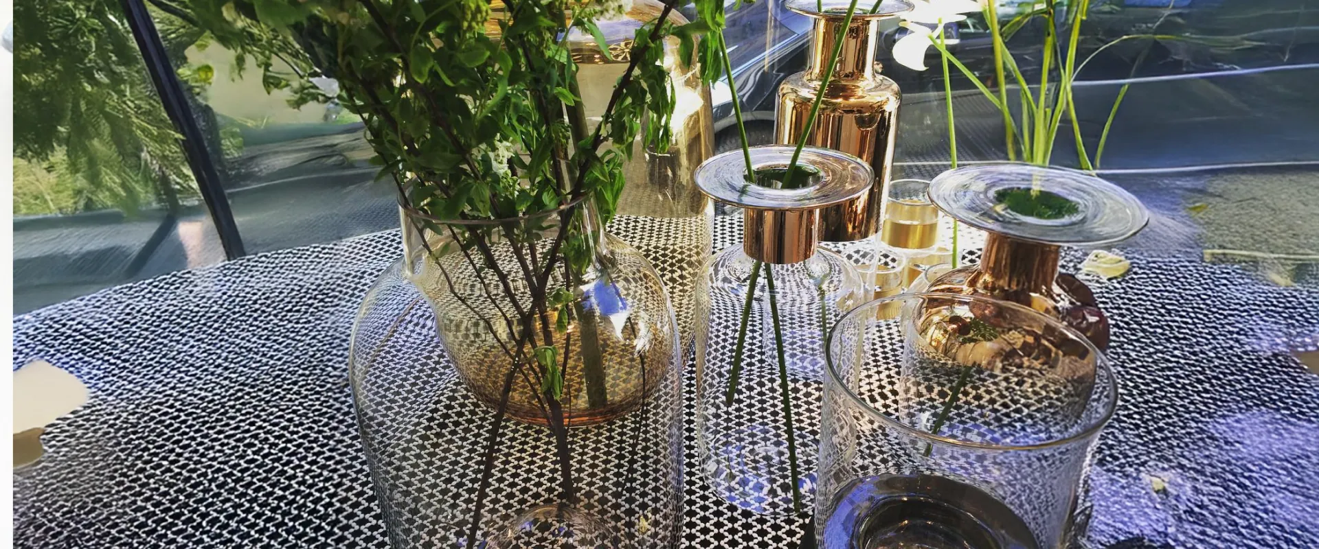 Vases en verre et en cuivre garnis de fleurs, sur une table en métal ajouré