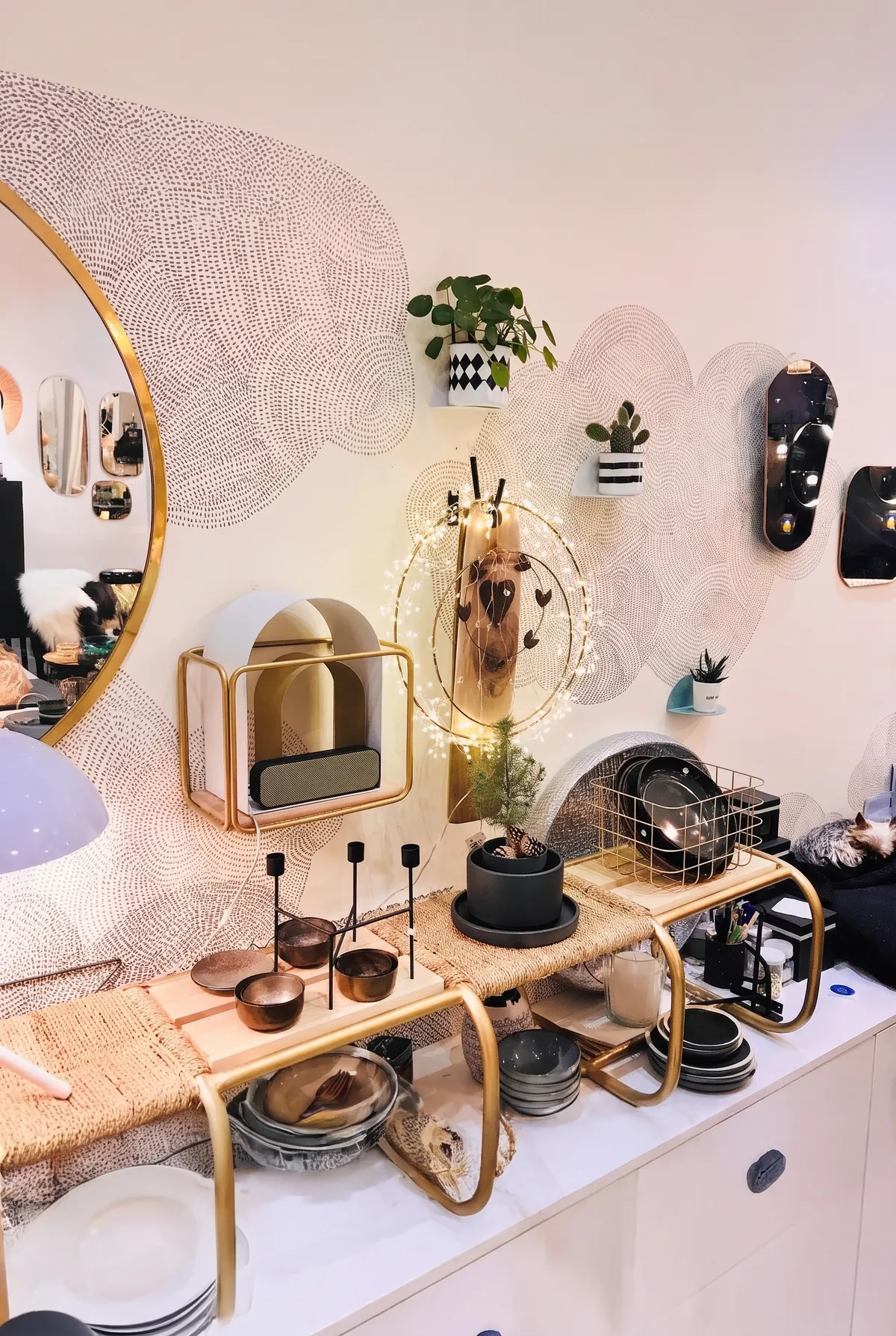 Un mur de la boutique : miroirs, étagères dorées, vaisselle et bougeoirs