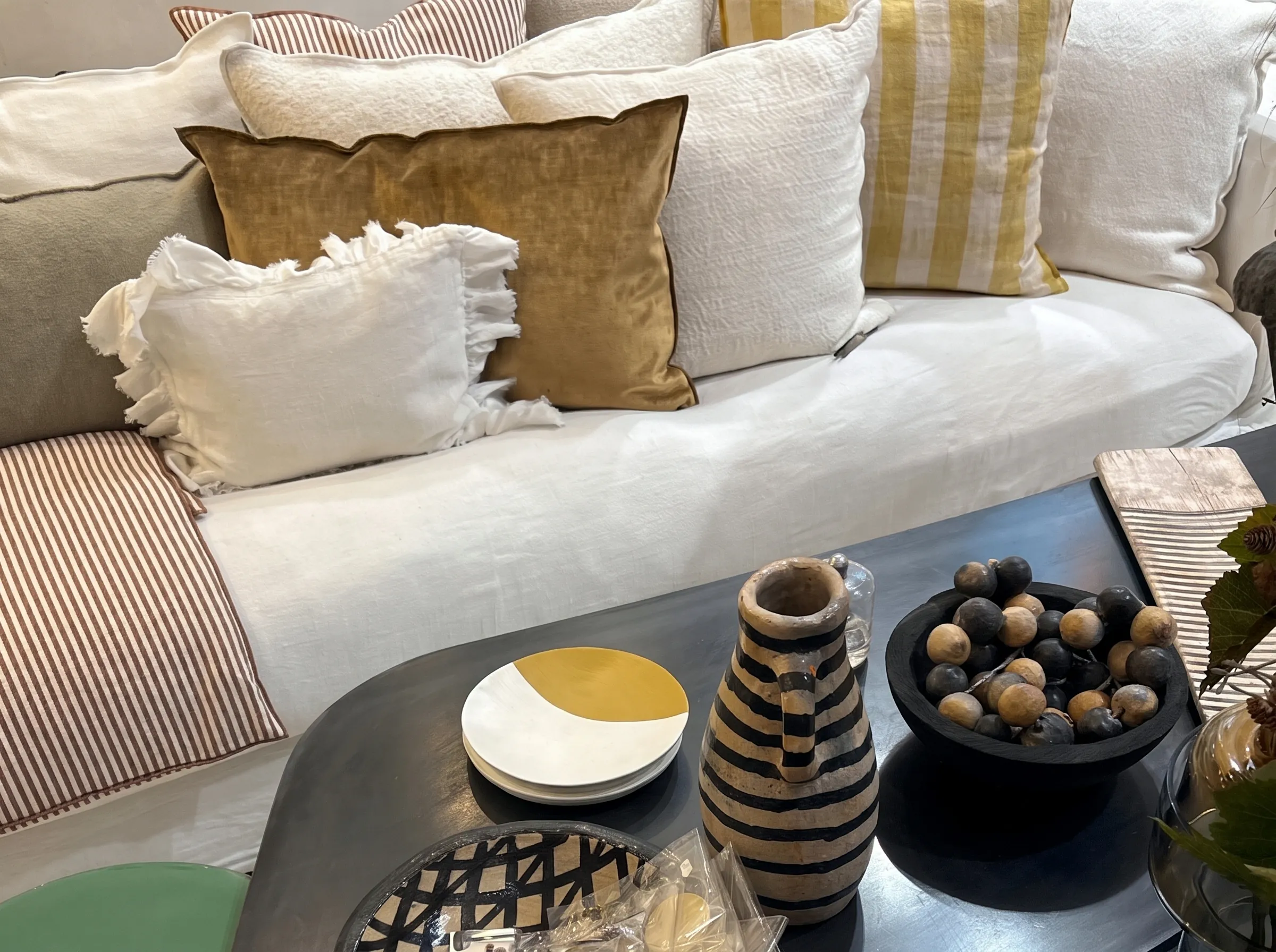 Canapé blanc garni de coussins, table basse et objets en céramique