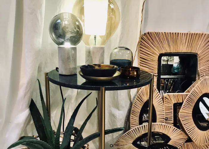 Lampes à globe sur un guéridon en marbre noir, à côté de miroirs en raphia