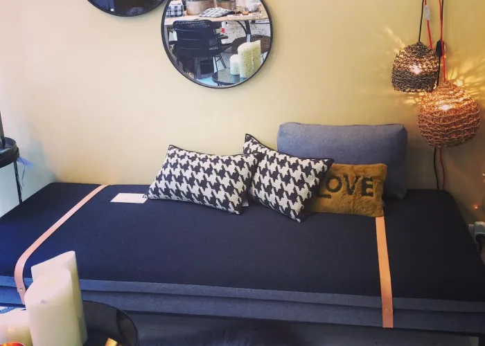 Banquette bleu marine garnie de coussins pied-de-poule et d'un coussin « LOVE », sous deux suspensions en métal