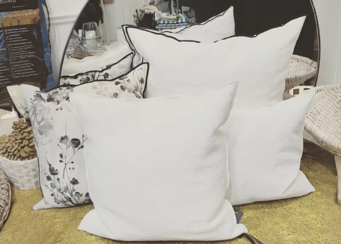 Grands coussins en lin blanc et coussin à fleurs sur un lit de la boutique
